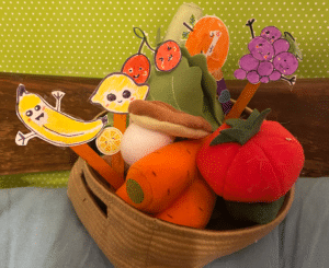 a photo of a mix of props for my ESL classes including Ikea plush toys of vegetables and home made props of cut out fruit on popsicle sticks