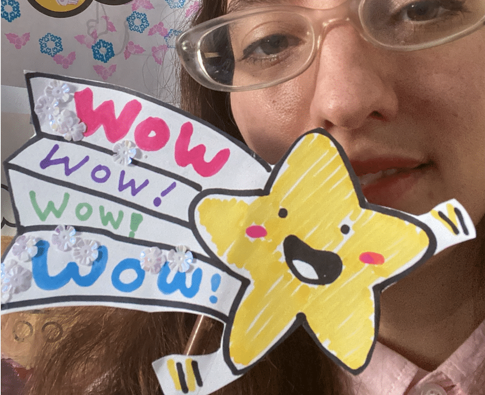 a photo of me holding a star on a popsicle stick that says 'wow' that I made to use for rewards when teaching ESL classes