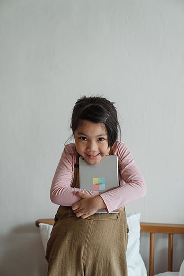 cute elementary school aged Chinese girl clutching her tablet while smiling