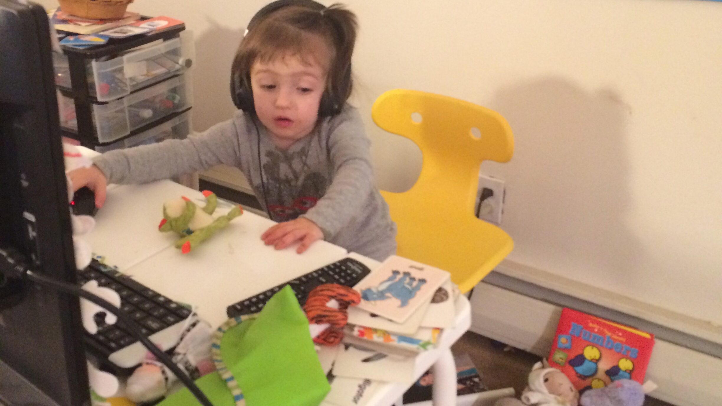 a photo of my daughter pretending to teach English online and sitting in my ESL classroom wearing my headphones
