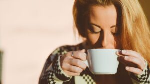 a photo of a woman sipping from a cup and wearing a sweater and looking comfortable