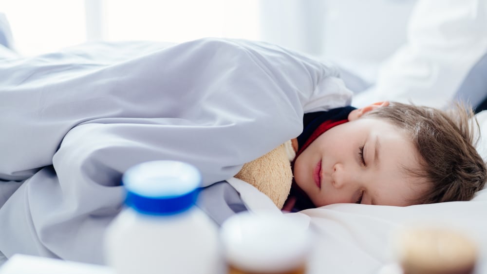 a boy sleeping in bed next to medication 