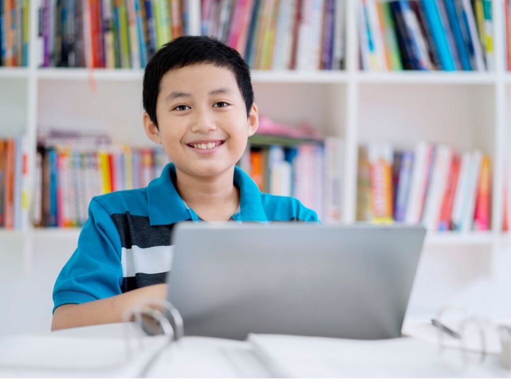 elementary school boy student smiling while learning online using a laptop in China