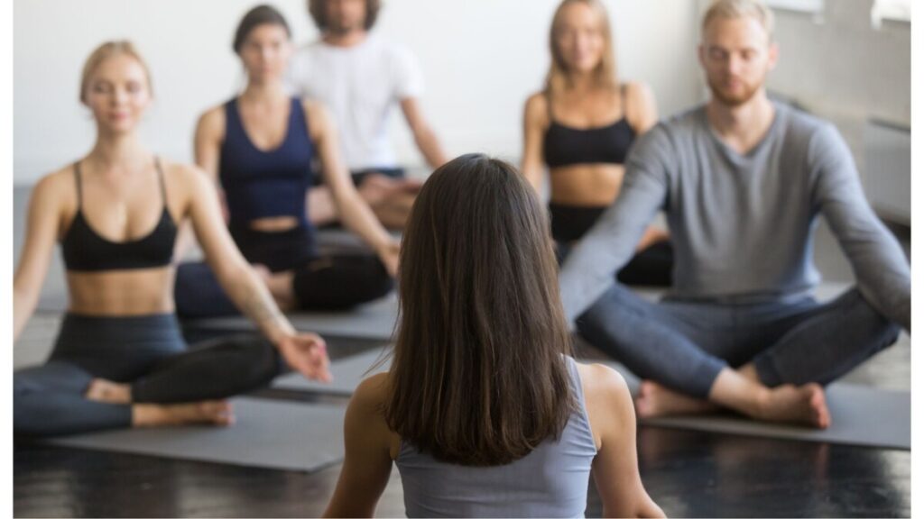 a photo of a woman leading a yoga group in mindfulness and meditation