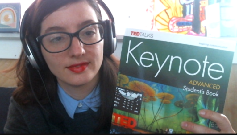 a photo of me holding up a Keynote Advanced Student's Book while wearing headphones