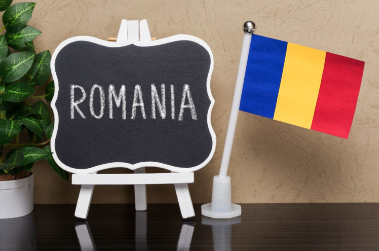 Romania written on a blackboard next to a Romanian flag
